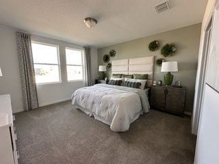 Model Home A serene bedroom with soft carpeting, elegant drapes, and stylish green accents on the wall.
