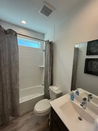 A modern bathroom featuring a sleek vanity, neutral tones, and elegant tiled shower with contemporary accents.