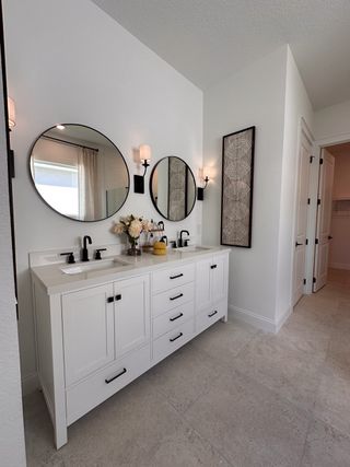 A modern bathroom featuring dual round mirrors above a sleek white vanity with stylish black fixtures and elegant wall decor.