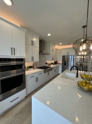 A modern kitchen featuring sleek white cabinets, a spacious island with quartz countertops, and stainless steel appliances.