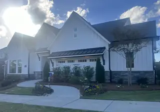 Elegant white-paneled home with stone accents and manicured garden in Carolina Riverside by Del Webb (Belmont, NC).