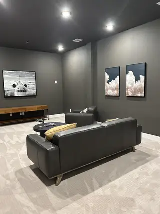 A contemporary media room with plush seating, modern artwork, and soft ambient lighting creating a cozy entertainment space.