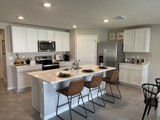 Model Home A modern kitchen with white cabinets, stainless steel appliances, and an island with seating. Perfect for entertaining.