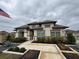 Charming modern exterior with stucco and stone accents, elegant landscaping in Veramendi by Coventry Homes (New Braunfels, TX).