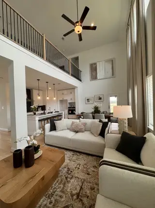 Model Home A spacious living area with high ceilings, modern decor, a cozy seating arrangement, and an elegant open kitchen.