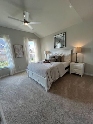 Model Home A cozy bedroom featuring plush carpet, elegant drapes, and soft lighting, offering a serene and inviting atmosphere.