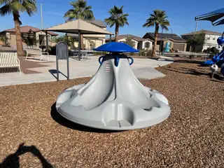 A vibrant playground with palm trees and seating in Ventana de Estrellas Enclaves by KB Home (Goodyear, AZ).