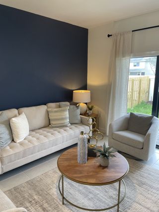 A cozy living room featuring a beige sofa, chic armchair, and a wooden coffee table with elegant decor.