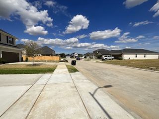 A serene suburban street with modern homes in Sweetgrass Village: Founders Collection by Beazer Homes (Crosby, TX).