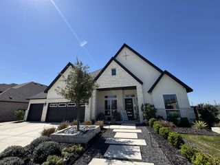 Street view A beautiful modern home with stone accents and a landscaped yard in Mesa Western by Chesmar Homes (Cibolo, TX).