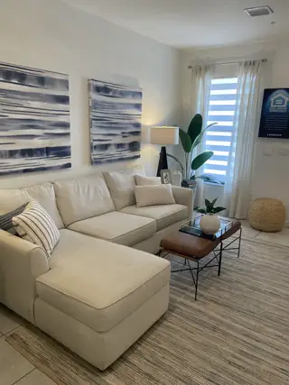 A cozy living room with a neutral sectional, abstract art, and modern accents in Tuscan Springs by Lennar (Pembroke Pines, FL).