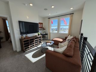 Model Home A cozy living area with a comfy brown sofa, TV, natural light, and a wooden media console. Perfect for relaxing and entertaining.