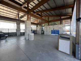 Community Amenities An airy pavilion with wooden beams and stone columns, featuring metal fencing and seating for gatherings.