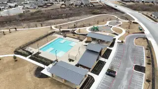 A scenic community center with a pool and playground in Emory Crossing 40s by Taylor Morrison (Hutto, TX).