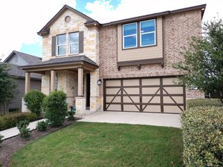 A charming two-story brick and stone home with a manicured lawn in Sonterra - Cool Water by KB Home (Jarrell, TX).