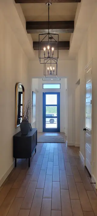 Model Home A welcoming foyer with wood-look tile flooring, elegant pendant lights, and a chic console table with decorative accents.
