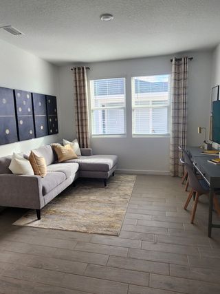 Model Home Modern living area with a cozy gray sectional, elegant artwork, and a sleek desk setup.