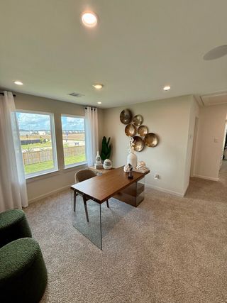 A cozy office with soft carpeting, modern decor, and a large window letting in natural light.