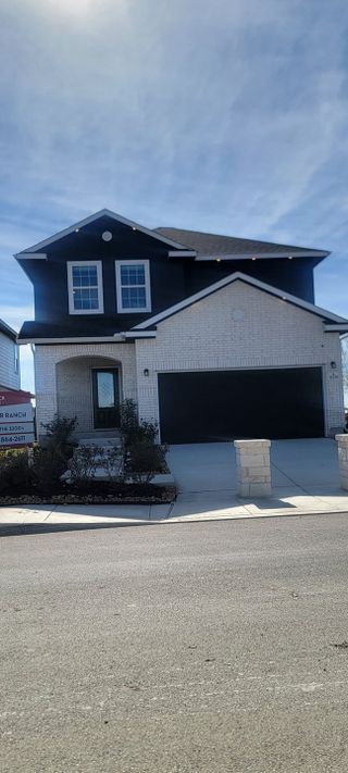 A modern two-story home with a dark trim and light brick in Katzer Ranch by CastleRock Communities (Converse, TX).
