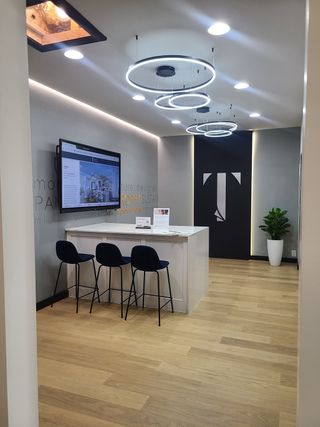 A sleek modern office with circular LED lighting, stylish stools, and wood floors, creating a welcoming and professional atmosphere.