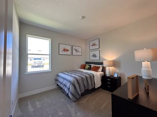 A cozy bedroom with dinosaur-themed decor, striped bedding, and soft lighting from matching table lamps.