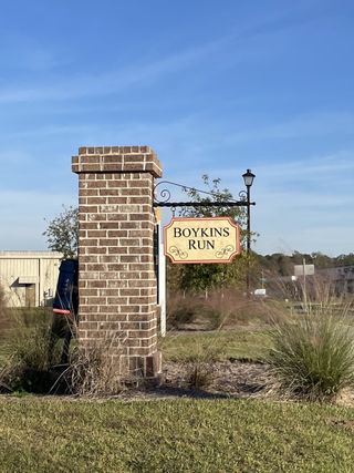 A welcoming brick entrance sign for Boykins Run Townhomes by DRB Homes in Moncks Corner, SC, set amidst lush greenery.