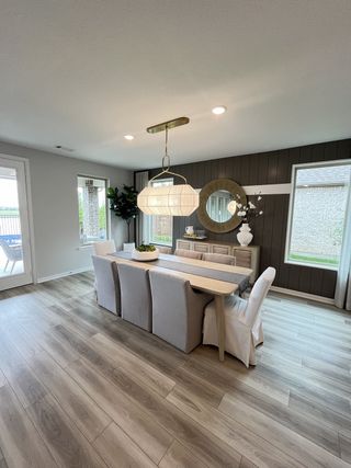 Model Home A sleek dining area with a modern chandelier, wood flooring, and large windows creating a bright, airy atmosphere.
