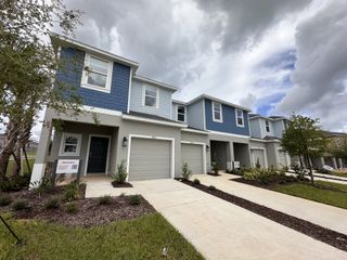 A modern townhouse with blue accents and landscaped front yards in Waterstone by Taylor Morrison (Mascotte, FL).