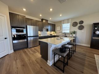 Spacious kitchen with dark wood cabinets, stainless steel appliances, and a bright island with seating.