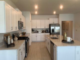 A modern kitchen with sleek white cabinets, stainless steel appliances, and elegant recessed lighting.