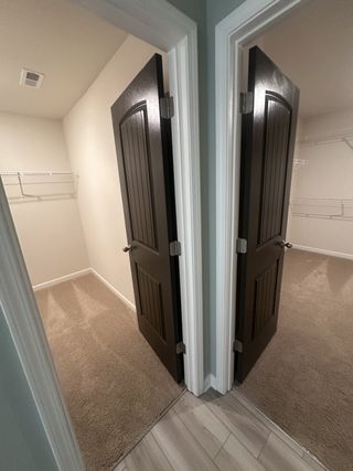 Model Home A large walk-in closet with ample shelving and soft carpeting in Dacula, GA.