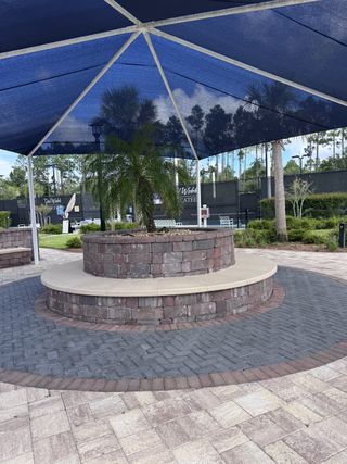 A charming stone patio with a shaded seating area in Del Webb Nocatee by Del Webb (Ponte Vedra, FL).