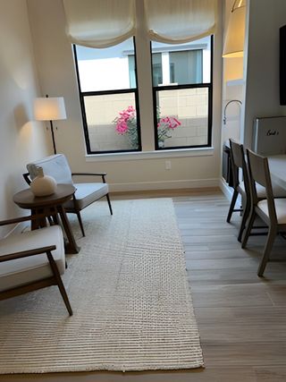 A cozy seating area with neutral tones, soft lighting, and a view of vibrant flowers outside the window.