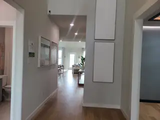 A bright hallway with modern art, wood flooring, and an open view to the living area.