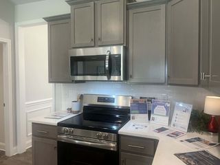 A modern kitchen with sleek gray cabinets, stainless steel appliances, and a crisp white subway tile backsplash.