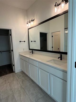 A modern bathroom with dual sinks, sleek black fixtures, and elegant lighting, featuring ample storage and a large mirror.